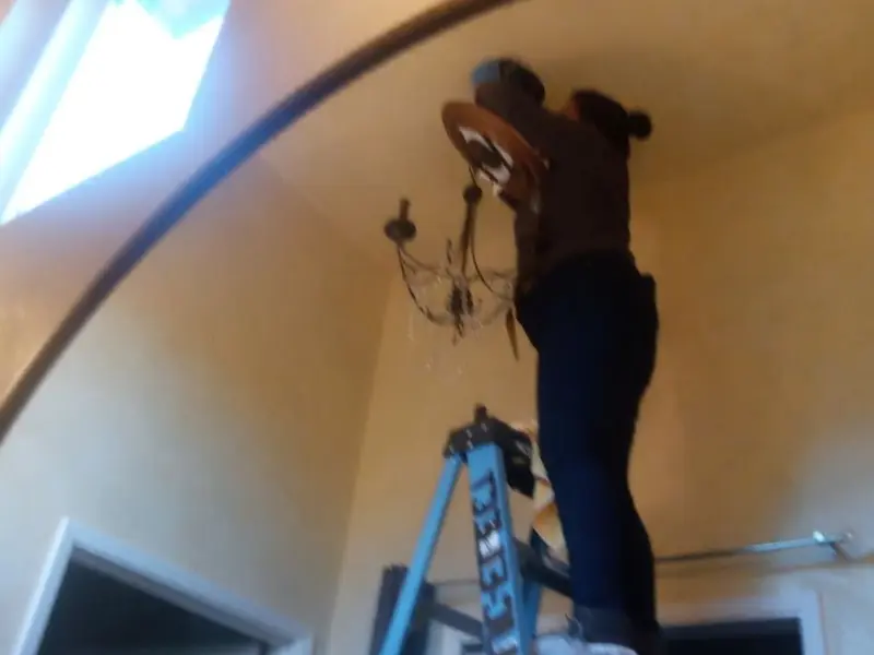 Electrician installing a chandelier in a St. Johns residence